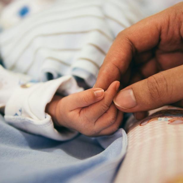 Person, die den Zeigefinger des Babys hält