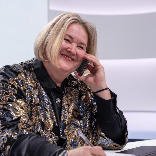 Anna Hergan telefoniert lächelnd am Schreibtisch.