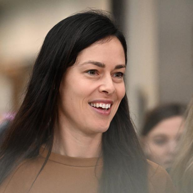 Eine lächelnde Ana Ivanovic mit langem, dunklem Haar trägt ein braunes Oberteil.