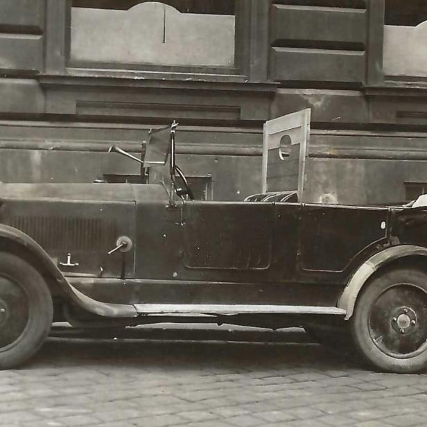 Altes schwarzes Cabrio vor einem Gebäude geparkt.