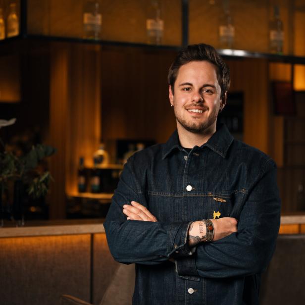 Bartender of the Year 2026 Yannik Seeber steht lächelnd vor einer Bar. 