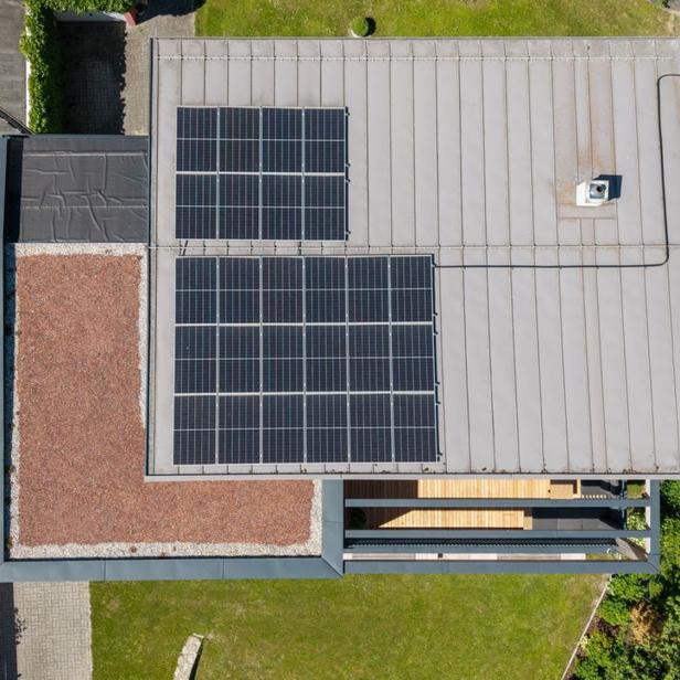 Luftaufnahme eines modernisierten Hausdachs mit Solarmodulen.