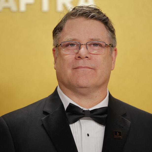 Sean Astin trägt einen schwarzen Smoking mit Fliege vor einem gelben Hintergrund mit dem SAG-AFTRA-Logo.