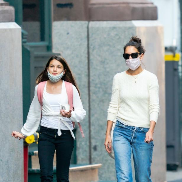 Suri Cruise geht mit Katie Holmes maskiert durch eine Straße in New York.
