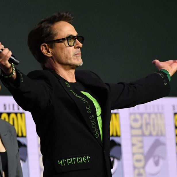 Robert Downey Jr. steht mit ausgebreiteten Armen und einem Mikrofon auf der Bühne der San Diego Comic-Con neben Hayley Atwell.