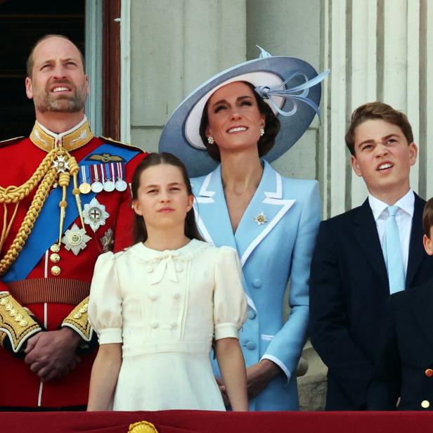 Prinz William, Prinzessin Kate und ihre Kinder George, Charlotte und Louis stehen auf einem Balkon und blicken gemeinsam nach oben.