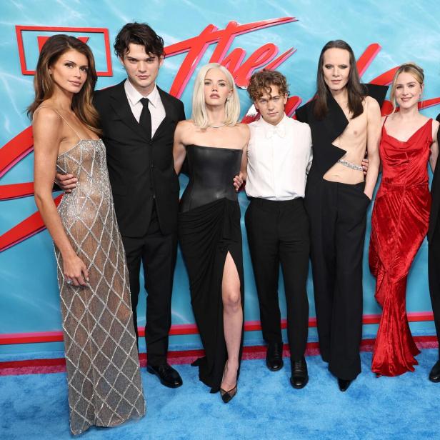 Kaia Gerber, Homer Gere und andere posieren gemeinsam vor einer blauen Wand mit Palmenmotiven bei einer Filmpremiere.