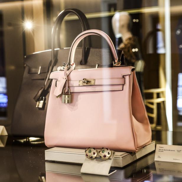 Rosa Handtasche mit Schloss in einer Luxusvitrine, daneben passende Ohrringe.