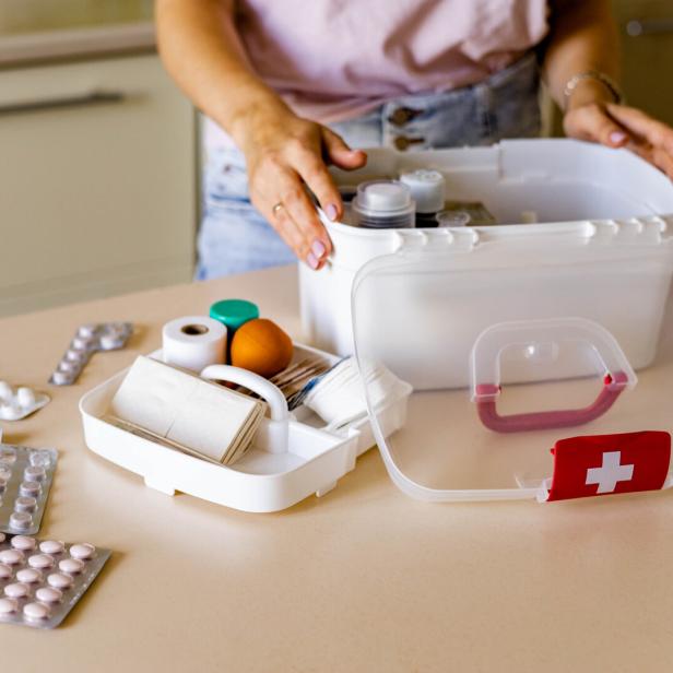 Closeup female hand placing medicament domestic first aid kit. Storage organization emergency supply