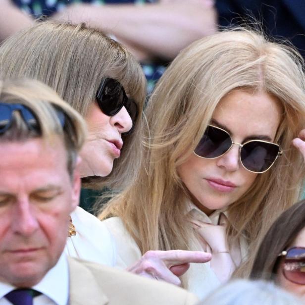 Anna Wintour und Nicole Kidman sitzen nebeneinander auf der Tribüne und tragen beide eine Sonnenbrille.