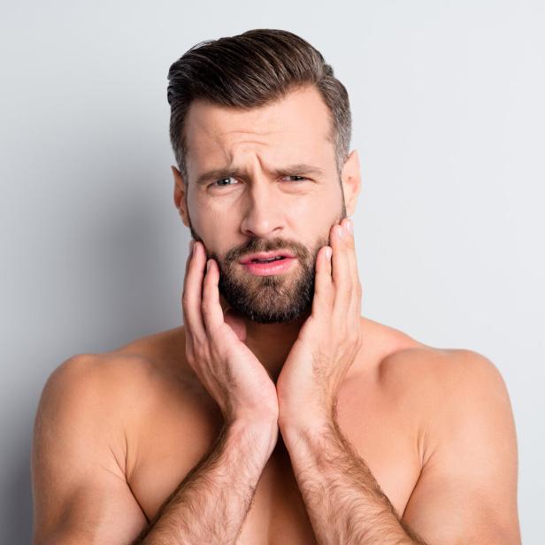 Photo of young handsome man unhappy sad upset displeased problem hand touch beard isolated over grey color background