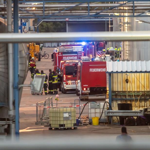 Feuerwehrleute und Einsatzfahrzeuge in einem Industriegelände.
