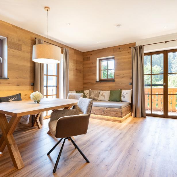 Helles Ferienappartement mit Holzwänden, Sitznische und Blick ins Grüne.
