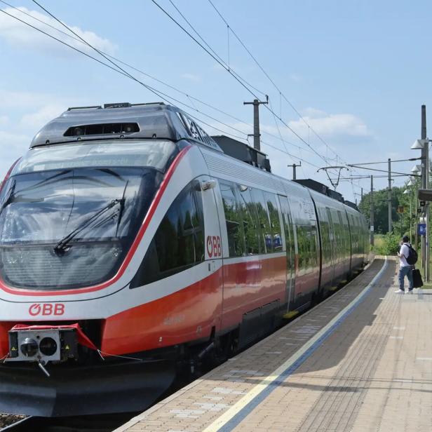 ÖBB-Zug an einem Bahnsteig, daneben wartet eine Person mit Gepäck.
