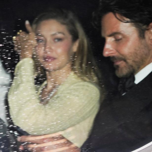 Gigi Hadid und Bradley Cooper sitzen bei Nacht in einem Auto, wobei die Scheibe mit Regentropfen bedeckt ist.