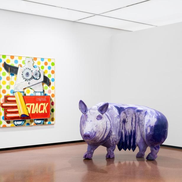 Violettes Schwein vor farbigem „Snack“-Gemälde in einem Ausstellungsraum.