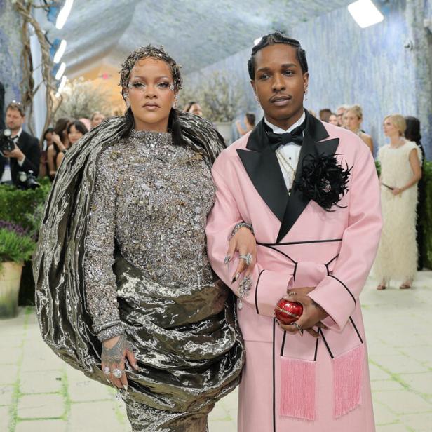 Rihanna in einem silbernen, strukturierten Kleid und Asap Rocky in einem rosa Mantel posieren gemeinsam auf dem roten Teppich.