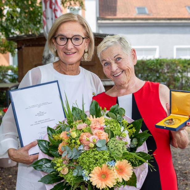 Johanna Mikl-Leitner überreicht Jazz Gitti Urkunde, Medaille und Blumen.