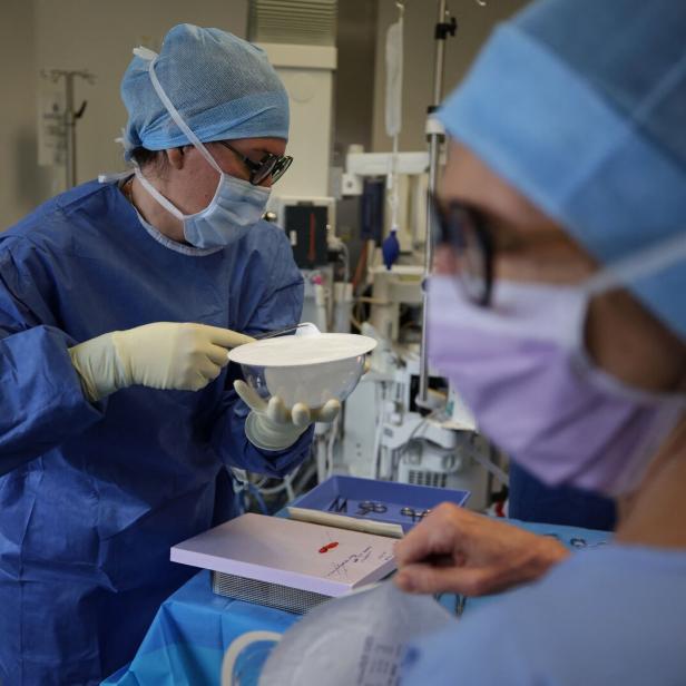 Zwei medizinische Fachkräfte in OP-Kleidung bereiten in einem Krankenhaus sterile Instrumente und Materialien für einen Eingriff vor.