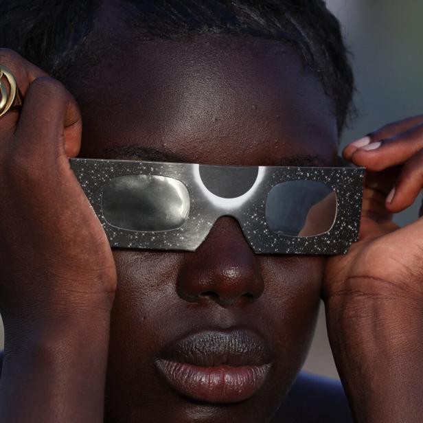 A woman observes a partial solar eclipse in Dakar