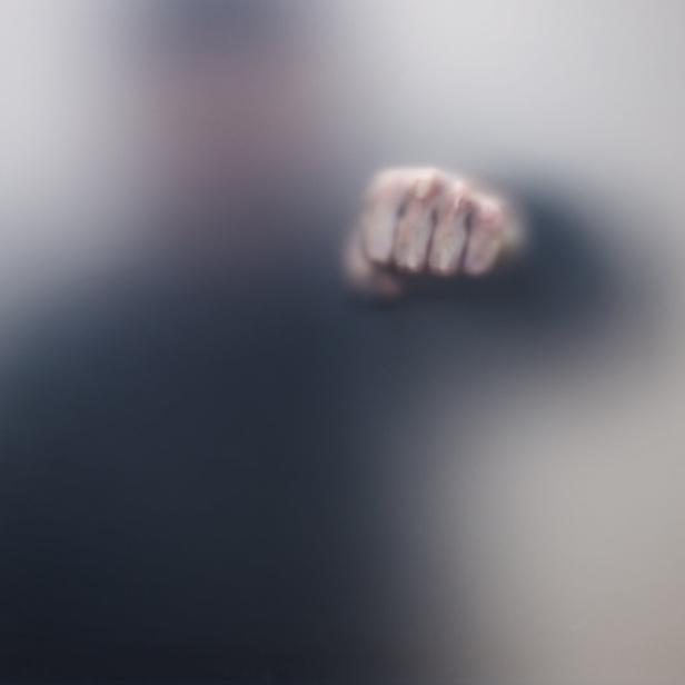Unschärfefoto einer geballten Hand hinter milchigem Glas.