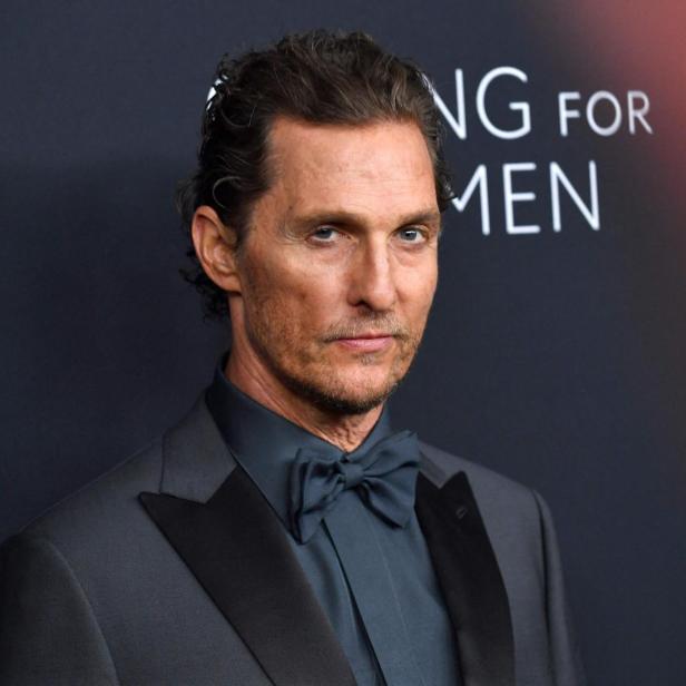 Matthew McConaughey trägt einen dunklen Anzug mit Fliege vor einem Hintergrund mit der Aufschrift „Kering Foundation“.