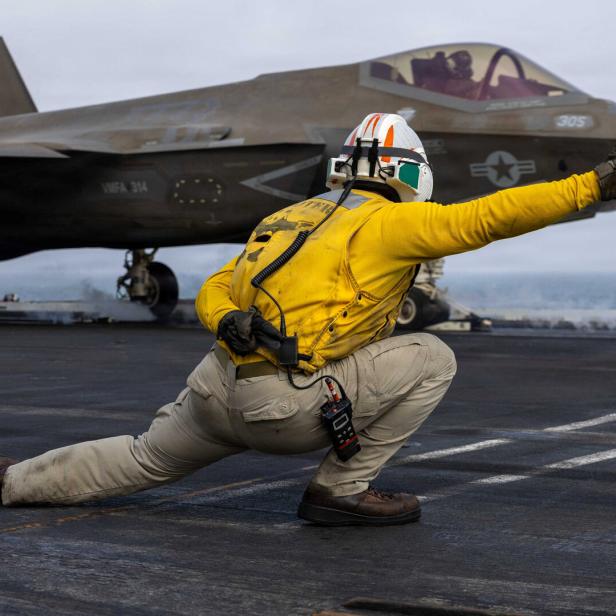 A U.S. sailor launches an F-35C Lightning II from the flight deck of Nimitz-class aircraft carrier USS Abraham Lincoln