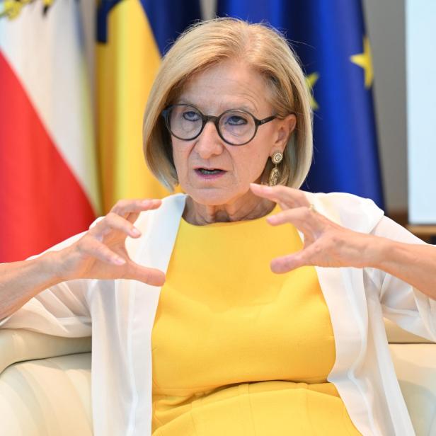 Die Politikerin Johanna Mikl-Leitner spricht gestikulierend vor österreichischen und europäischen Flaggen.