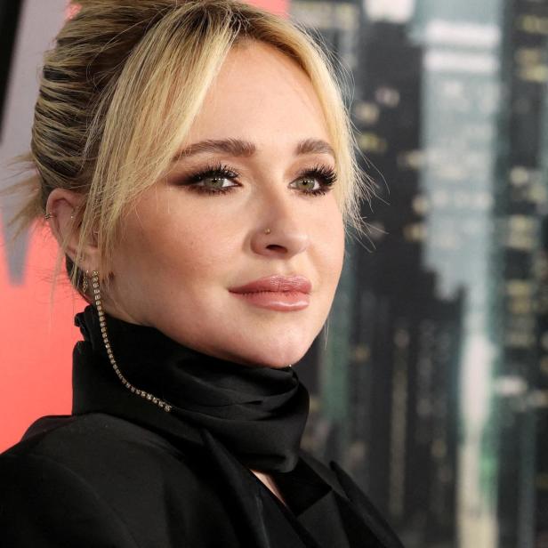 Hayden Panettiere mit blondem Dutt und schwarzem Oberteil vor einem verschwommenen Hintergrund.