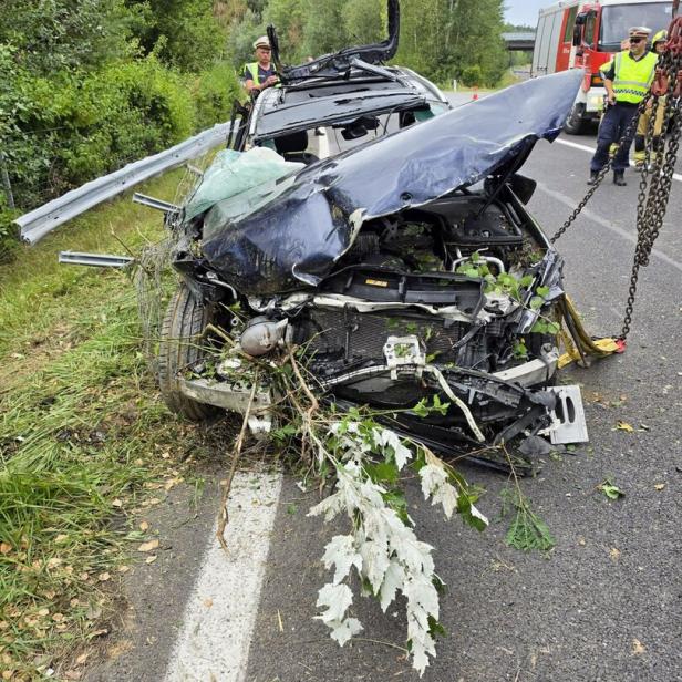Schwer verunfalltes Auto auf der Straße, Einsatzkräfte sichern die Unfallstelle.