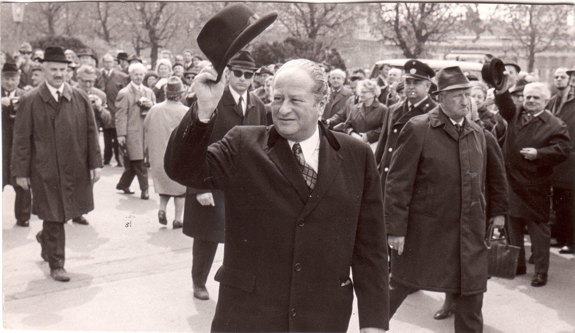 Bundeskanzler Bruno Kreisky grüßt mit Hut in der Menge.