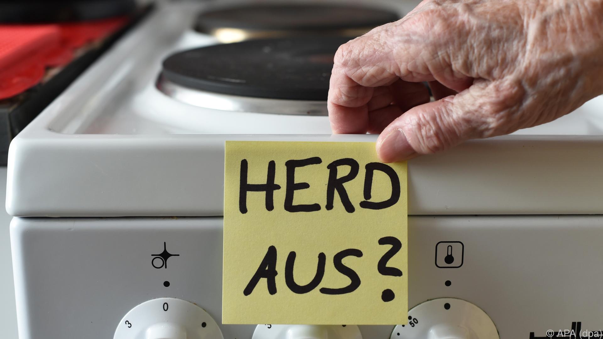 Ein Zettel mit der Aufschrift „Herd aus?“ hängt an einem Herd.