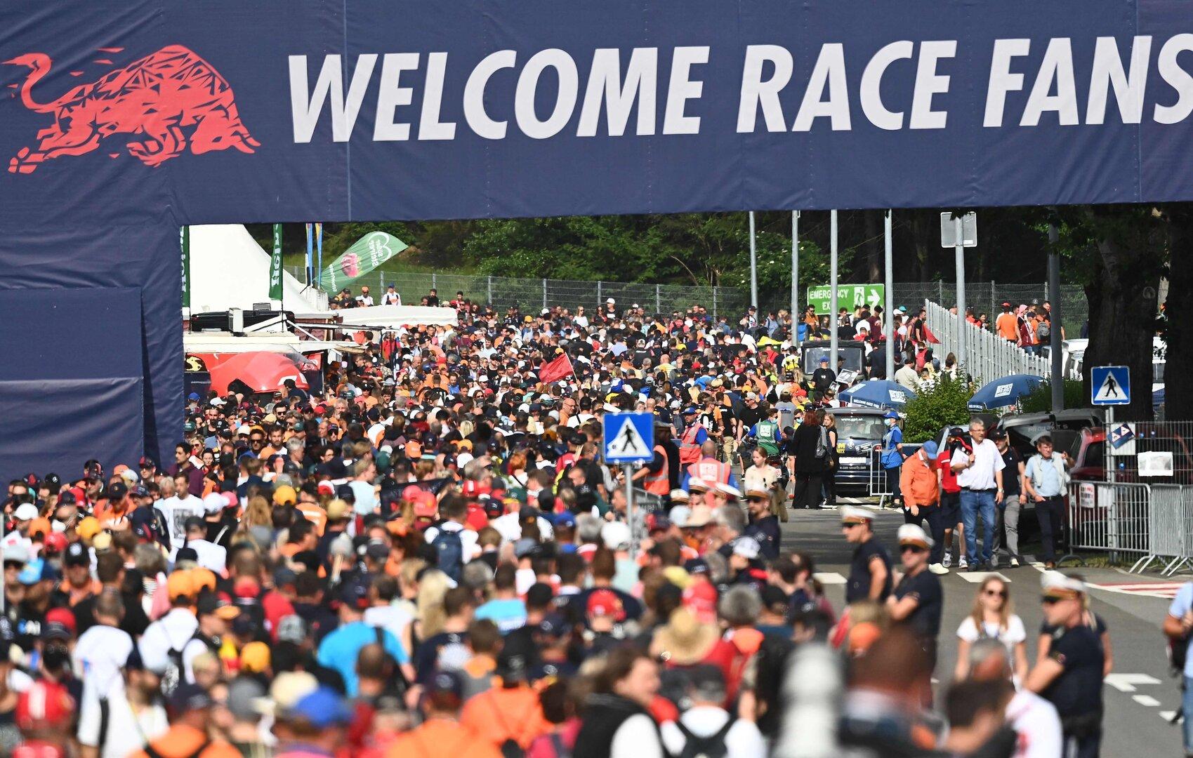 Große Menschenmenge unter einem „WELCOME RACE FANS“-Banner bei einer Motorsportveranstaltung.