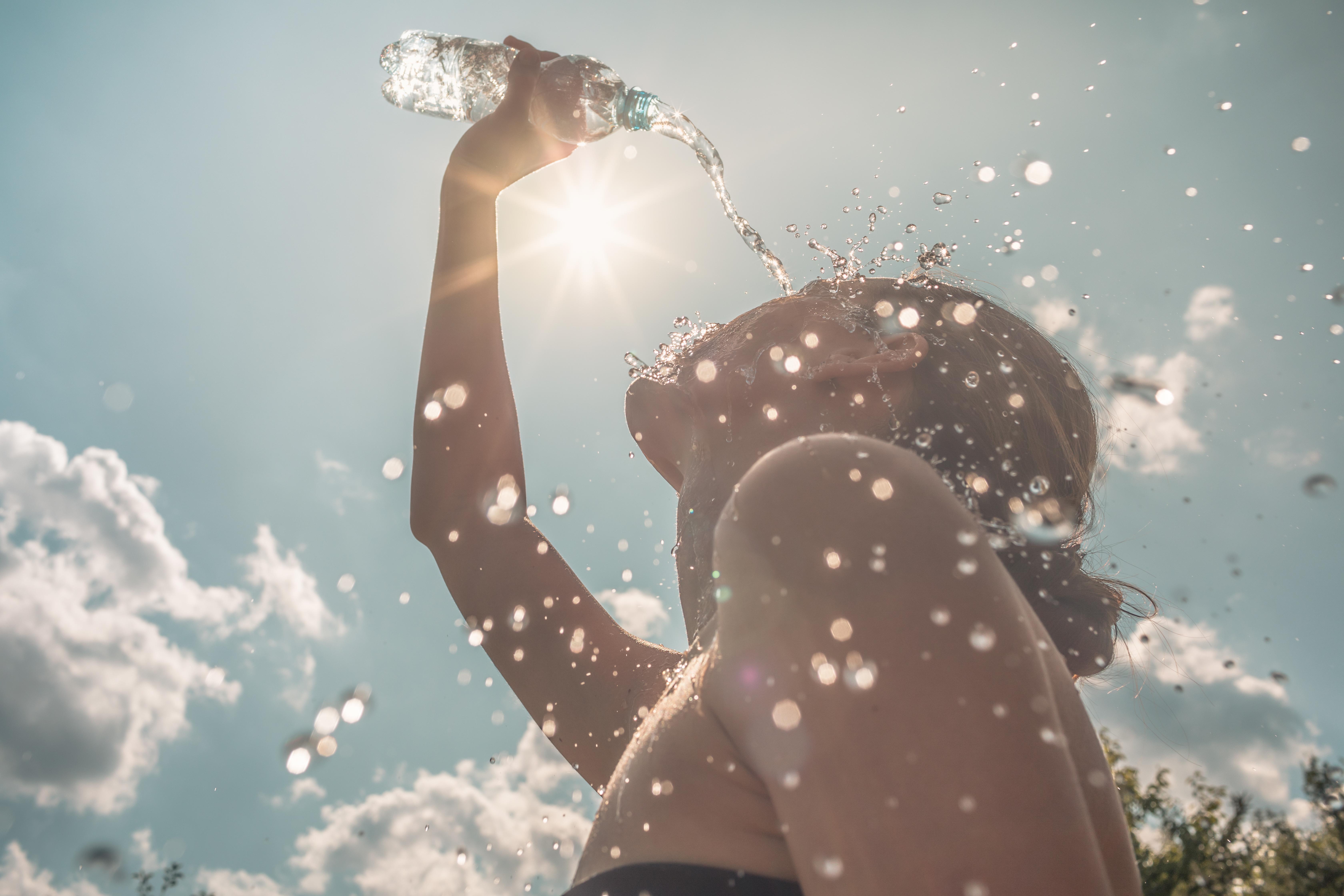 Eine Frau kühlt sich an einem heißen Sommertag mit Wasser ab.