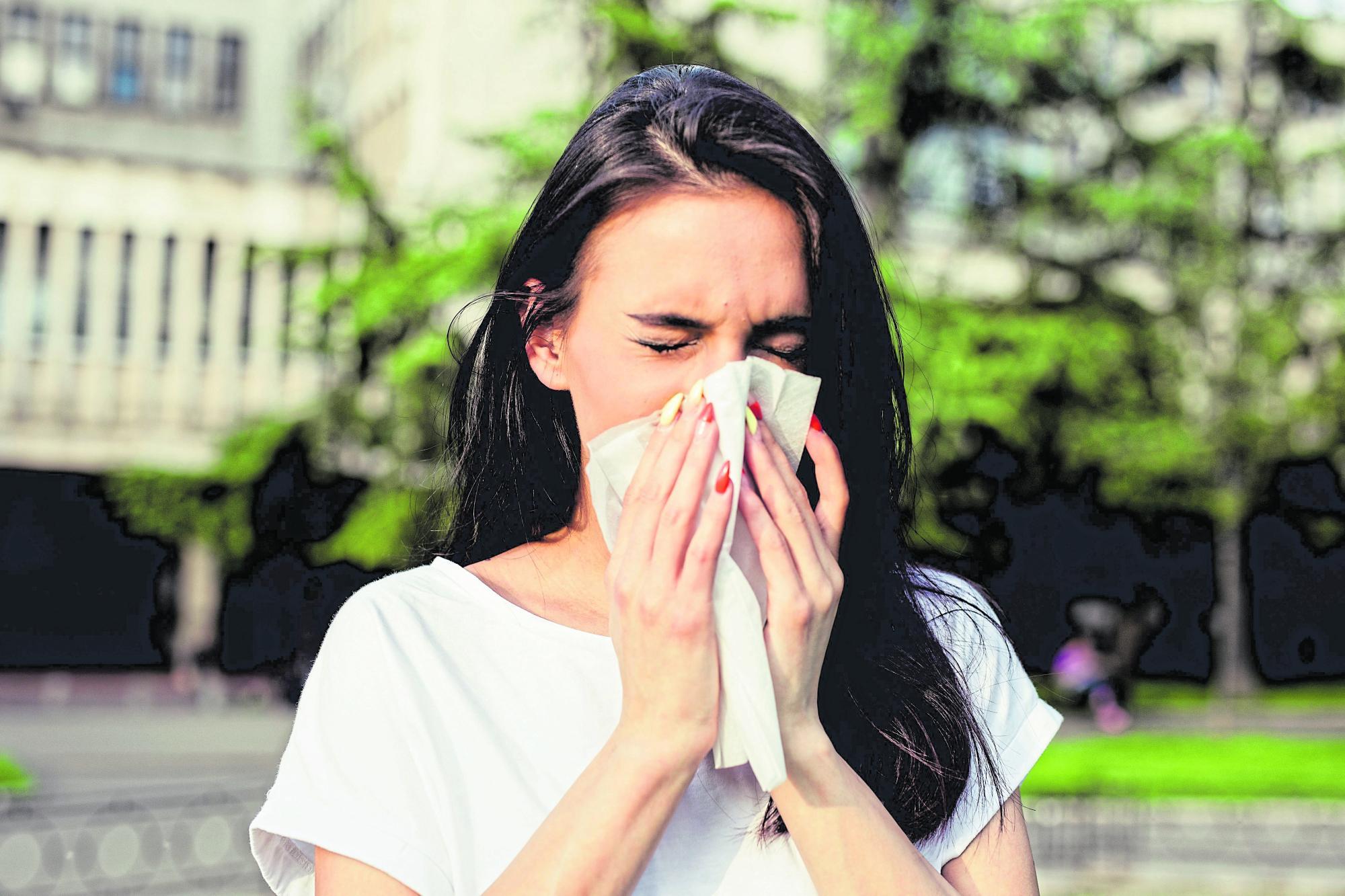 Frau niest in ein Taschentuch.