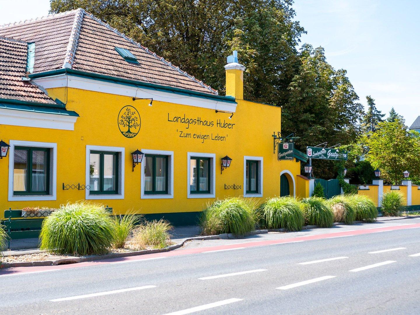 Das gelbe Landgasthaus Huber mit der Aufschrift „Zum ewigen Leben“.