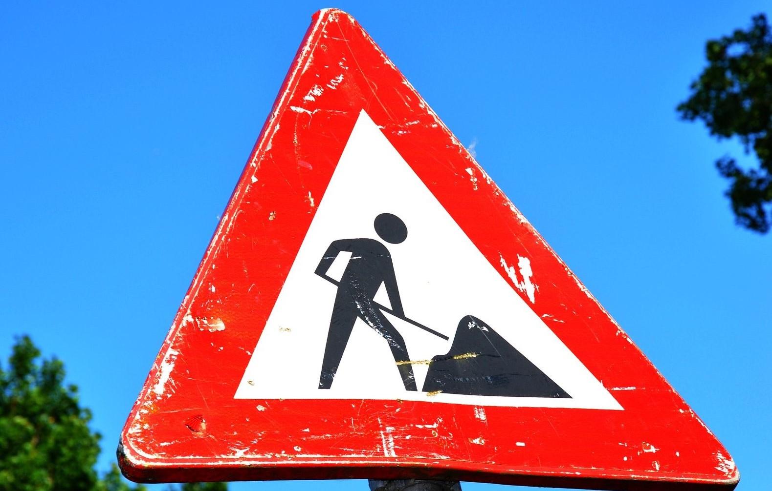 Ein rot-weißes Warnschild kündigt Straßenbauarbeiten an.