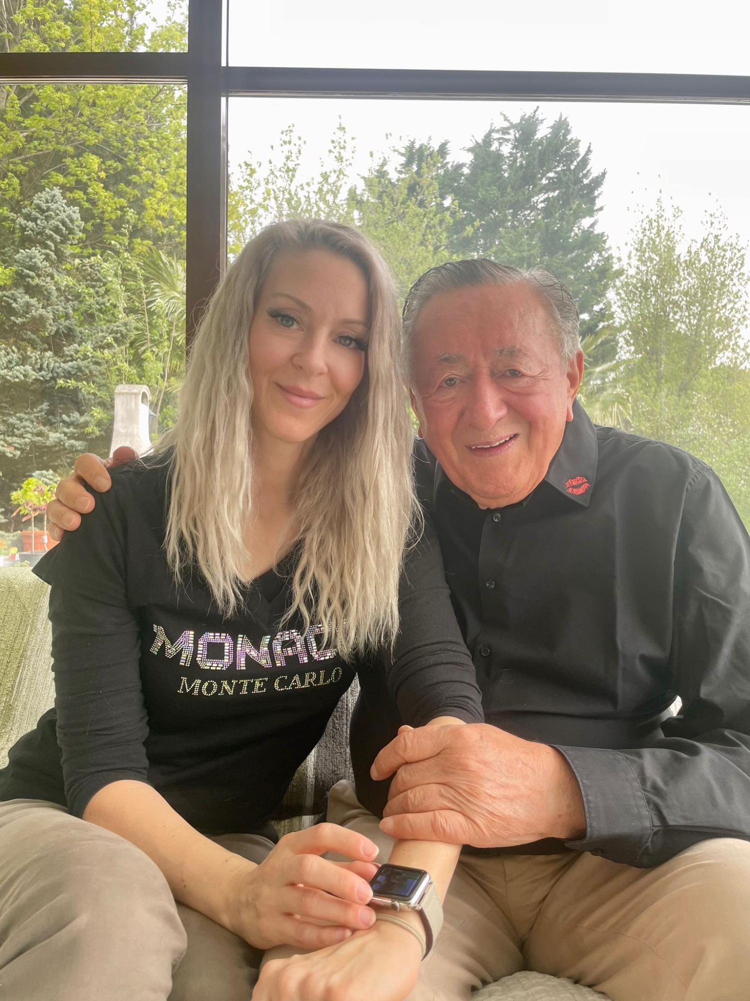 Eine Frau mit blonden Haaren und ein älterer Mann posieren für ein Foto.