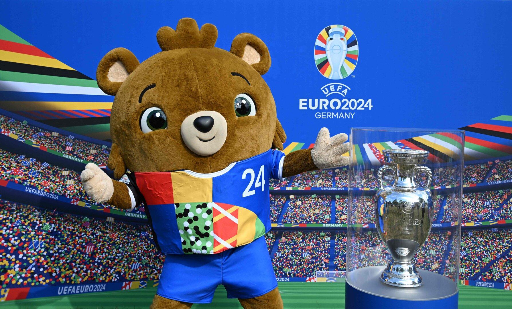 Das Maskottchen der UEFA EURO 2024 posiert neben der Trophäe.