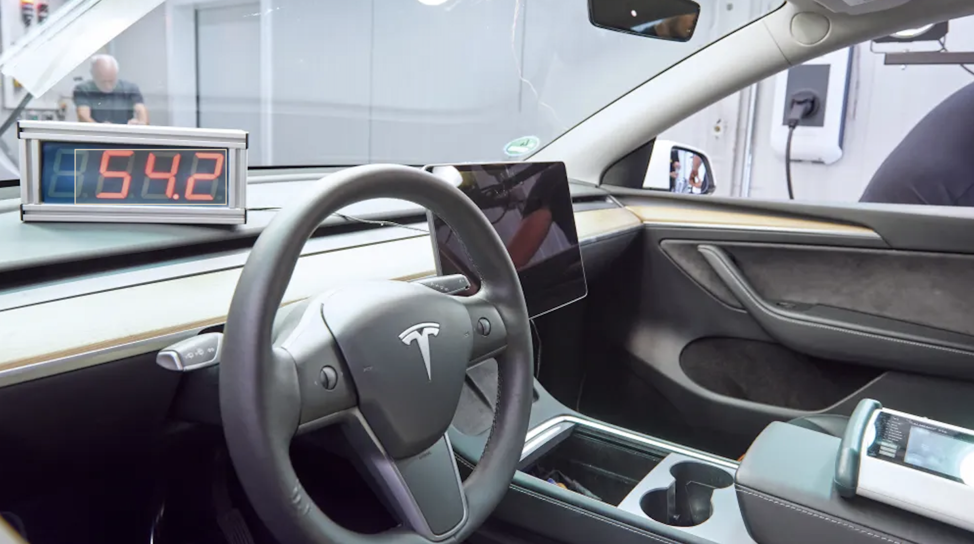 Innenansicht eines Tesla mit einem digitalen Messgerät auf dem Armaturenbrett, das 54,2 anzeigt.
