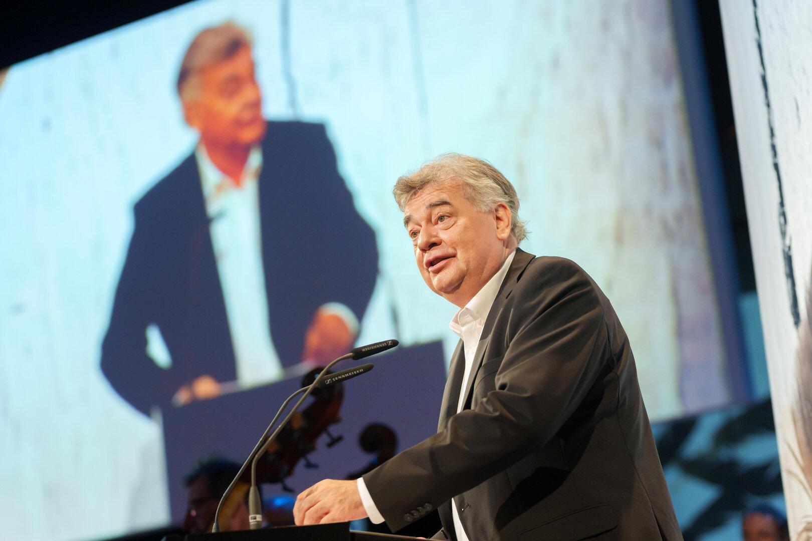 Ein Mann hält eine Rede vor einem großen Publikum.