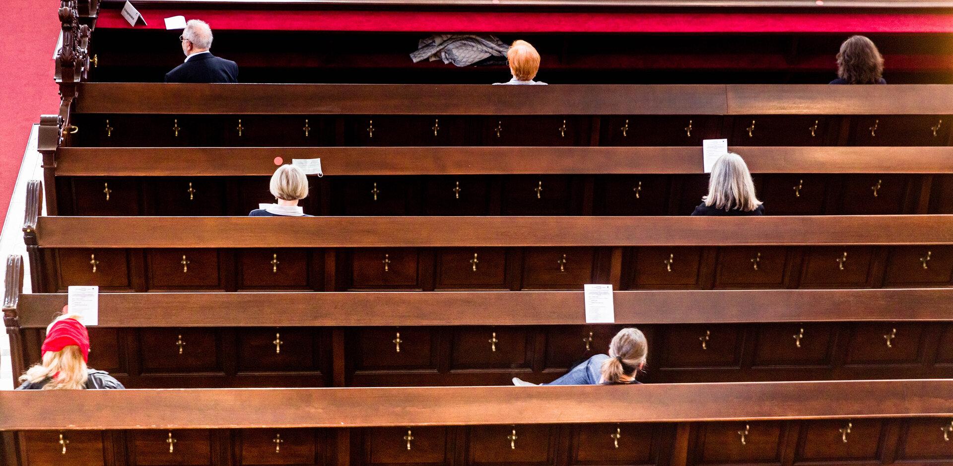Mehrere Personen sitzen in Kirchenbänken.