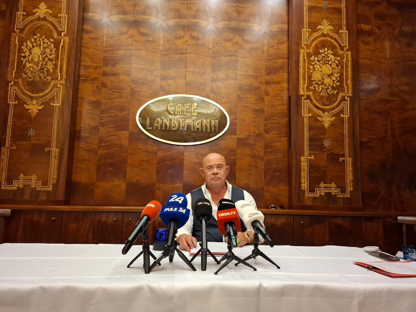 Ein Mann sitzt vor Mikrofonen im Café Landtmann.