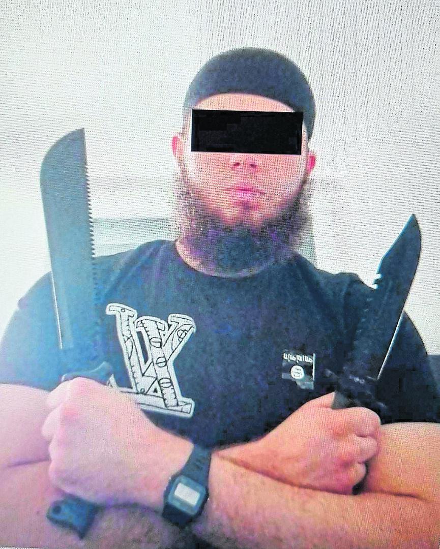 Ein Mann mit Bart und Mütze posiert mit zwei Messern vor einem hellen Hintergrund.