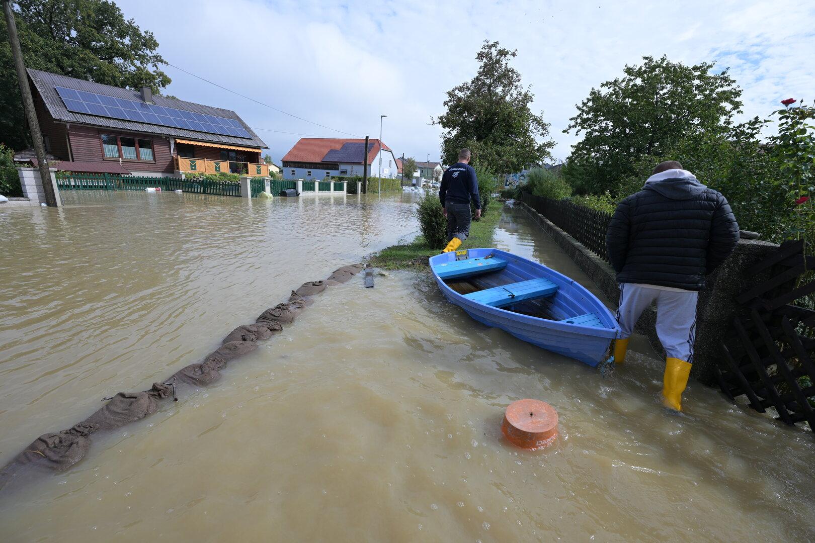 Überflutung eines Wohngebiets mit einem blauen Boot am Straßenrand.