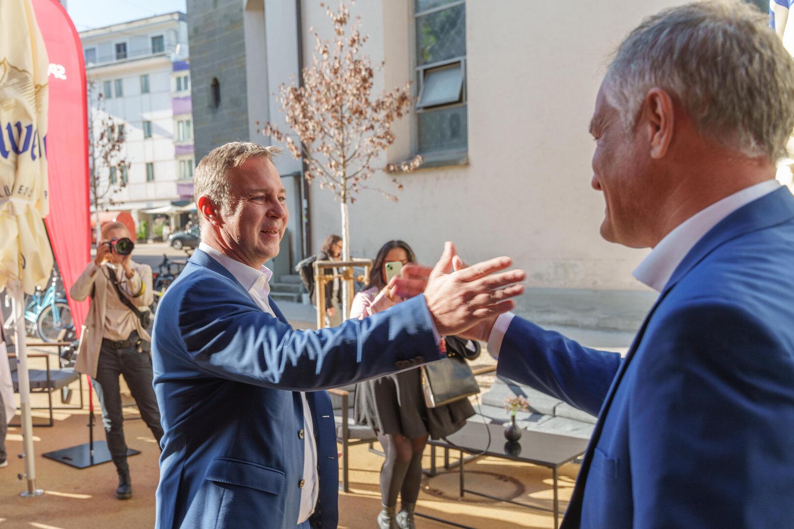 Zwei Männer in Anzügen geben sich die Hand.