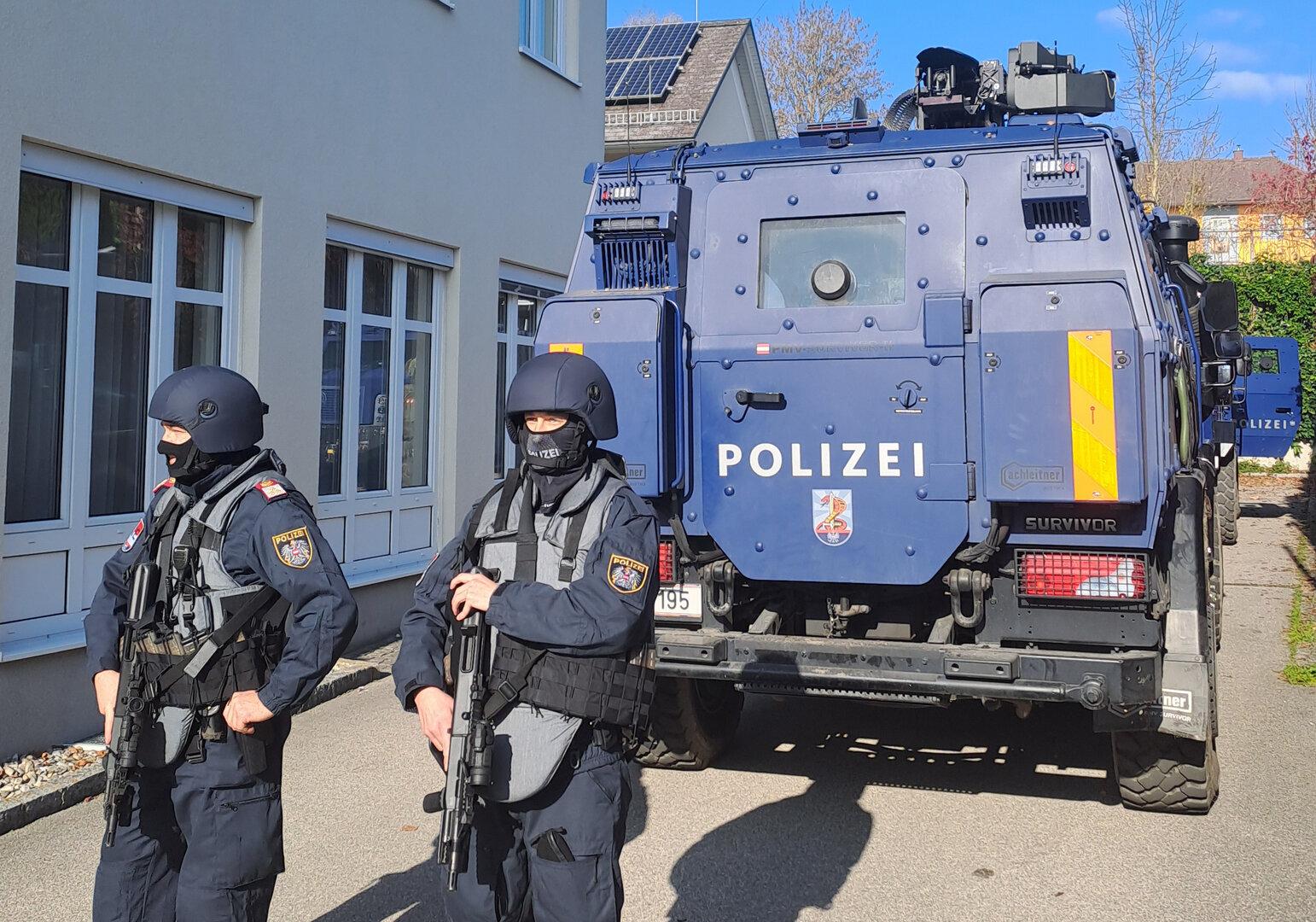 Zwei österreichische Polizisten stehen vor einem blauen Polizeifahrzeug vom Typ „Survivor“.
