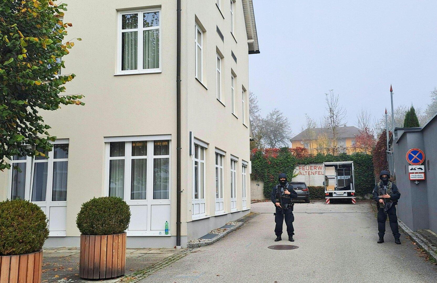 Zwei bewaffnete Polizisten stehen vor einem Gebäude der Feuerwehr Altenfelden.