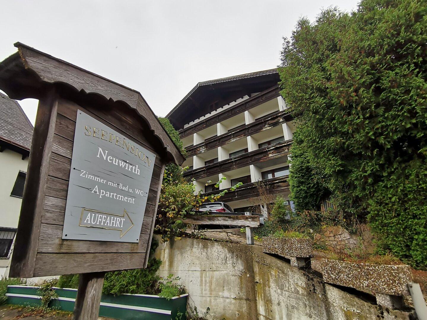 Ein Schild weist auf die „Seepension Neuwirth“ hin, mit Zimmern und Apartments.