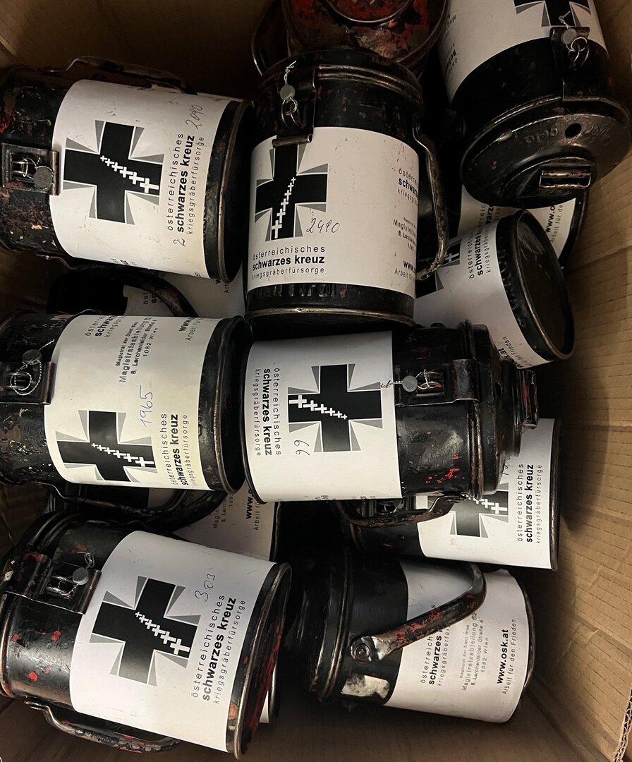 Mehrere Dosen des Österreichischen Schwarzen Kreuzes in einem Karton.